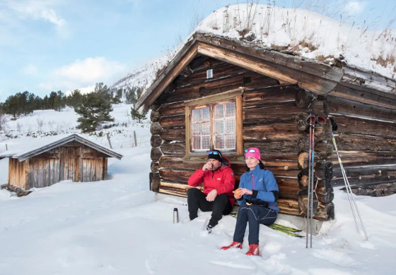 Bei der Langlauftour Jotunheim Loipe rasten 2 Langläufer vor einer Blockhütte